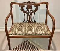 Front view of bench showing carved backrest and upholstered seat