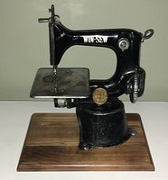 Front view of the black cast iron Win-Sew miniature sewing machine on wood base