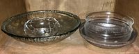 A large textured smoky glass bowl holding three smaller clear glass bowls of varying designs and sizes.