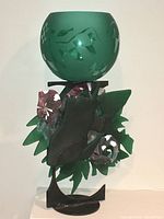 Front view of the sculpture showing the green frosted glass globe atop floral metal base