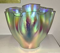 Front view of a iridescent glass vase with ruffled edge showing color play of green, pink, and blue