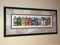 Framed print with colorful newspaper boxes and stylized newspaper text background, showing overall view hanging on wall.