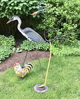 Wide shot of all three garden decor pieces together on grass with bushes in background
