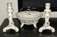 Overview of the complete three-piece German porcelain console set including two candlesticks and one centerpiece bowl, showing detailed floral and gold accents.