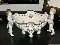 Full view of German porcelain centerpiece with two cherub figures holding the decorative bowl