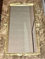 Top view of gilt brass rectangular tray with ornate scrolled edge design and mirrored surface.