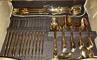 Photo showing the full flatware set in the storage case including various knives, forks, spoons, and serving pieces.