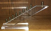 Full view of the vintage acrylic menorah showing its angled linear form and all nine candle holders in brass.