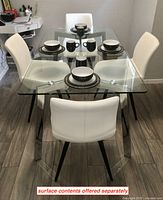 Front view of glass top table with four chairs arranged around it
