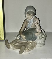 Front angle showing the girl figure sitting holding a goose with a basket beside her.