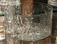 Side angle view of clear glass bowl showing textured floral and bubble motifs on the exterior surface