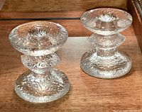 Pair of clear textured bubble glass candlesticks on wood surface, showing heights and base details.
