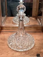 Front view of the crystal decanter standing upright showcasing the wide patterned base and clear fluted neck.