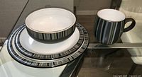 Dinner plate, lunch plate, bowl and mug displayed on glass table showing stripe pattern