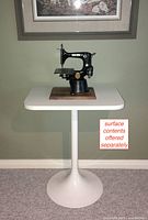 Small white rectangular side table with rounded edges and a single pedestal column tulip style base.