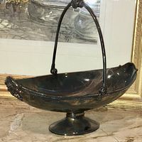 Front view of Victorian silver plated bread server showing curved handle, oval bowl, and pedestal base.