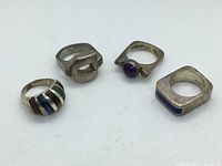 Four vintage sterling silver rings with diverse designs on white background