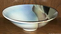 Side profile showing the bowl's outward sloping edges, glaze color variations on interior and exterior, and footed base.