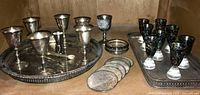 Wide view of all items arranged on the trays, showing goblets, coasters, shot glasses, and tongs.