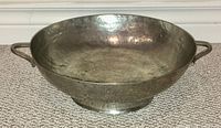 Front angled view showing the hand-hammered texture, bowl depth, handles and footed base.