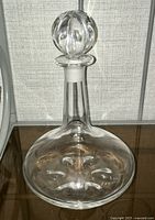 Full view of clear crystal decanter with wide round base and narrow neck, showing the shape and overall form.