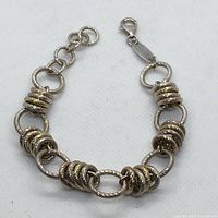 Full view of the vintage silver bracelet laid flat showing the textured oval links and gold-tone coiled ring clusters