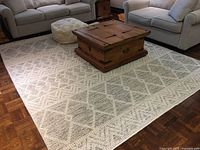 Full view of ivory rug beneath coffee table and seating