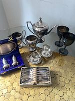 Photo showing entire lot including teapot, goblets, cream and sugar, egg cups, spoons and salt & pepper sets on a table.