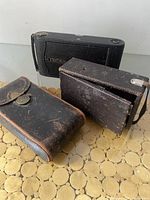 Three antique Kodak cameras: one folding pocket camera, one Eastman Primo No.1 folding bellows camera, and one Autographic Junior camera in case.