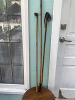 Three wooden gun cleaning rods of varying length placed vertically against a wall, showing overall set condition.
