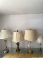 Full view of all four lamps side-by-side on glass surface.