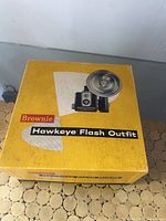 Original box with lid showing Brownie Hawkeye Flash Outfit branding and camera image.