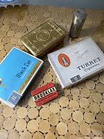 Top-down photo showing all 5 tins with distinct designs and branding.