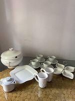 Wide shot of all items showing soup terrine, mugs, serving plate, divided tray, Mikasa cups and saucers, and teapot on round table