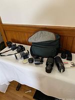 Group shot of camera, lenses, filters, teleconverter, cleaning kit and Lowepro bag on table