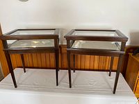 Pair of identical wood and glass display tables side by side