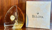 Front view of the sailboat-shaped crystal clock with yellow accent and Bulova box beside it