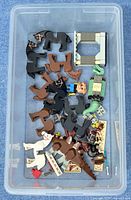 Top view of a small plastic tray holding assorted LEGO horses, a LEGO minifigure, and various LEGO pieces.