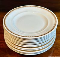 Stack of thirteen white bone china salad plates with Elizabethan pattern gold border