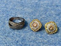 925 sterling silver marcasite ring alongside a pair of gold wash sterling silver stud earrings on blue surface.