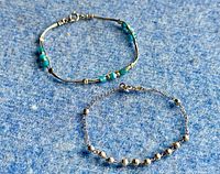 Two sterling silver bracelets on blue felt background showing overall condition and design difference; one bracelet with turquoise beads, other with faceted silver beads on chain.