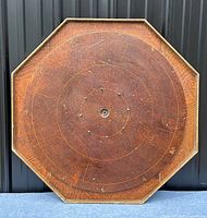 Full view of the octagonal crokinole board showing scoring rings and pegs with antique patina.
