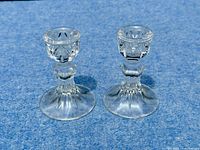 Pair of clear Waterford crystal candlesticks shown on a flat surface with blue background