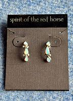 Front view of Zuni sterling silver earrings with lab opals on original packaging showing full design and brand name.