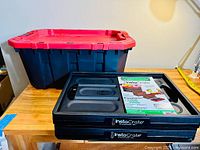 Two foldable InstaCrates and one large plastic storage bin with red lid on wooden surface.