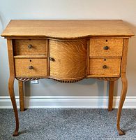 Full front view of sideboard showing drawers, central curved door, apron and legs