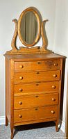 Front view of tiger oak high boy dresser with attached oval mirror