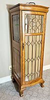 Full view of curio cabinet showing front leaded glass door, side glass panels, wood grain and bracket feet