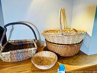 Four woven baskets displayed on a wooden surface showing different shapes and colors