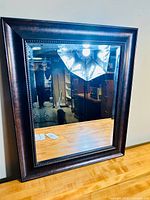 Full front view of the rectangular mirror with dark wood frame and beveled glass, showing clean reflective surface and polished frame.